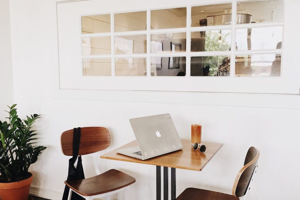 macbook on brown wooden dining table and chairs